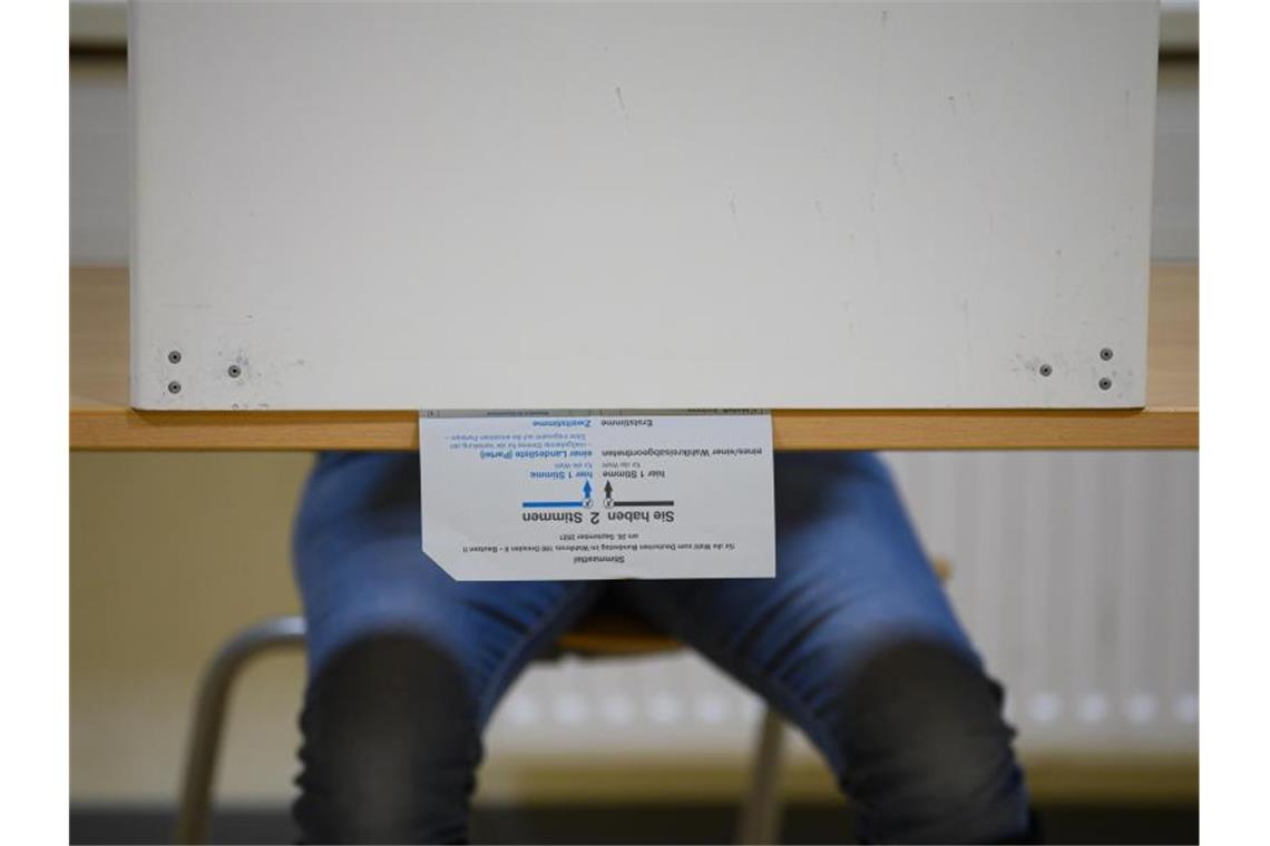 Ein Wählerin sitzt in Dresden bei der Stimmabgabe zur Bundestagswahl mit ihrem Stimmzettel in der Wahlkabine. Knapp 60,4 Millionen Deutsche sind aufgerufen, den neuen Bundestag zu wählen. Foto: Robert Michael/dpa-Zentralbild/dpa