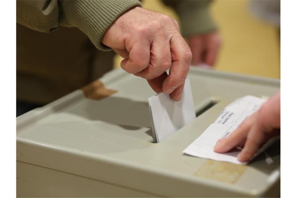 Landtagswahl: Strenge Corona-Regeln an der Wahlurne Ein Wahlberechtigter steckt seinen Stimmzettel in die Wahlurne in einem Wahlbüro. Foto: Matthias Bein/dpa-Zentralbild/dpa