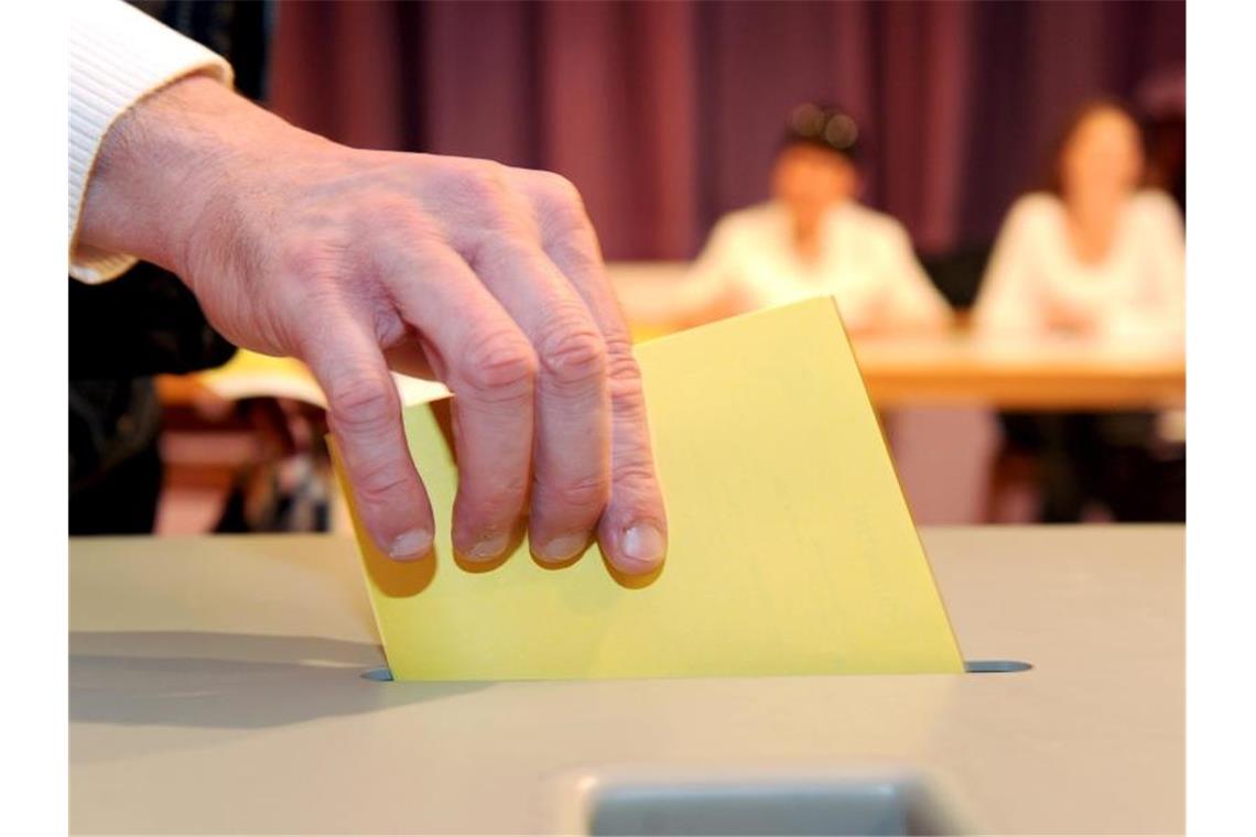 Ein Wahlzettel wird in eine Wahlurne gesteckt. Foto: Bernd Weissbrod/dpa/Illustration