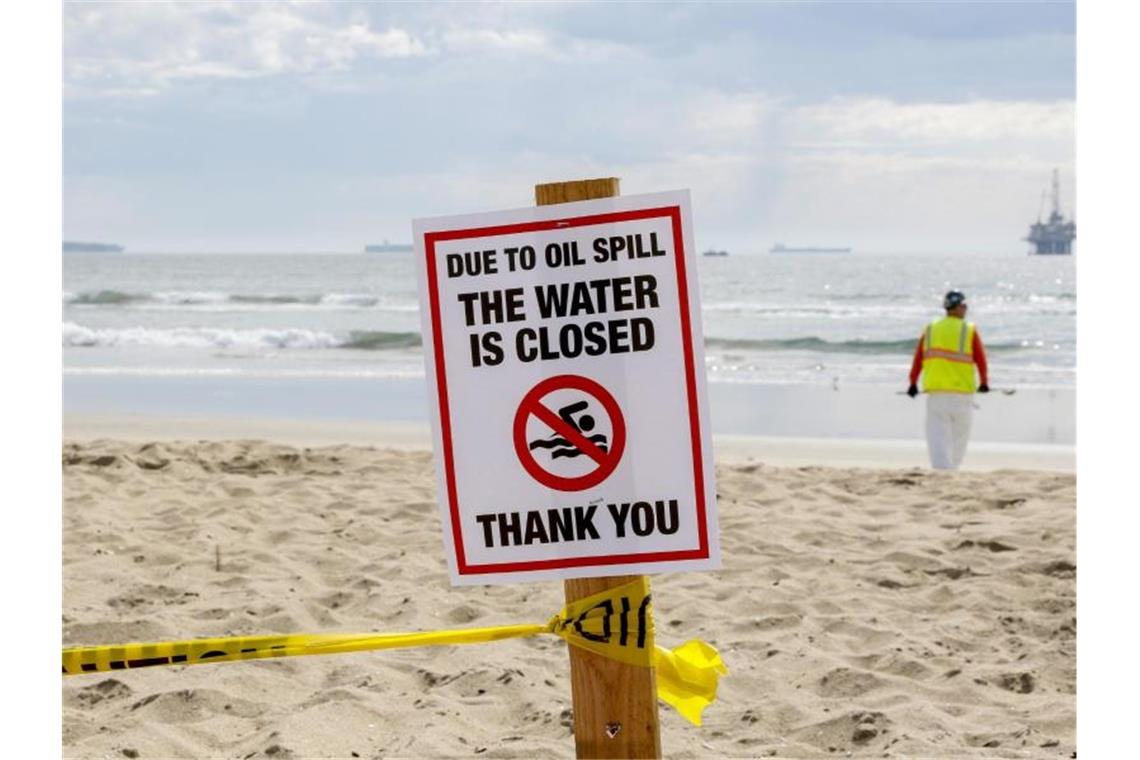 Ein Warnschild in Huntington Beach, im Hintergrund eine Ölplattform. Foto: Ron Lyon/ZUMA Press Wire/dpa