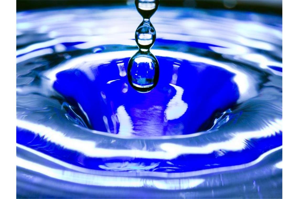 Ein Wassertropfen fällt in eine blaue Wasserschüssel. Foto: Jens Büttner/zb/dpa/Symbolbild