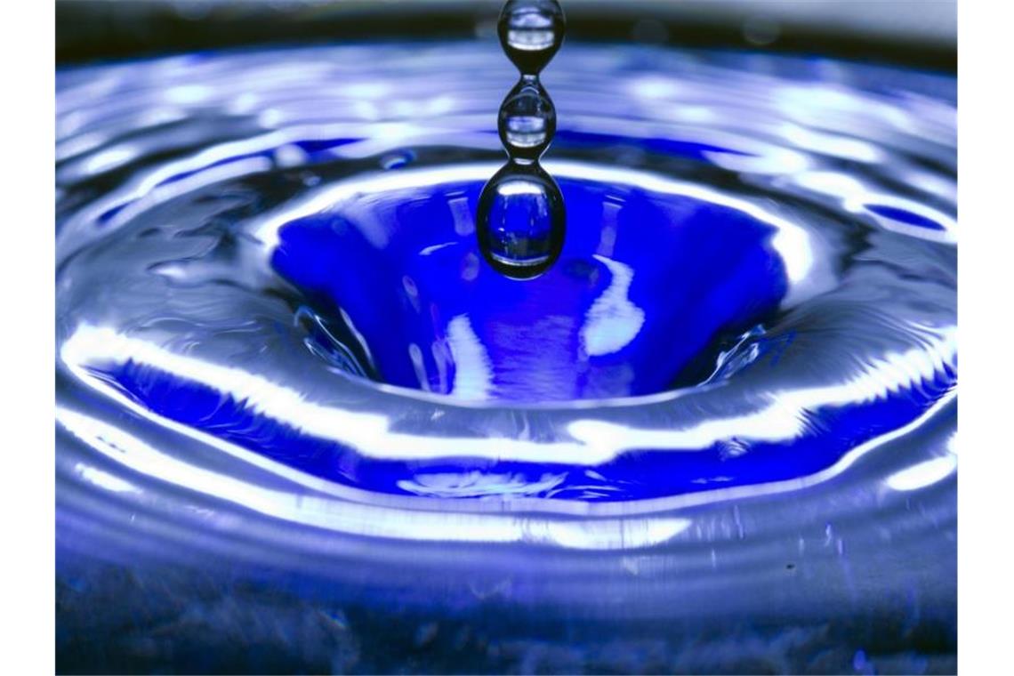 Städte im Land wollen mehr Trinkwasserbrunnen Ein Wassertropfen fällt in eine blaue Wasserschüssel. Foto: Jens Büttner/Archivbild