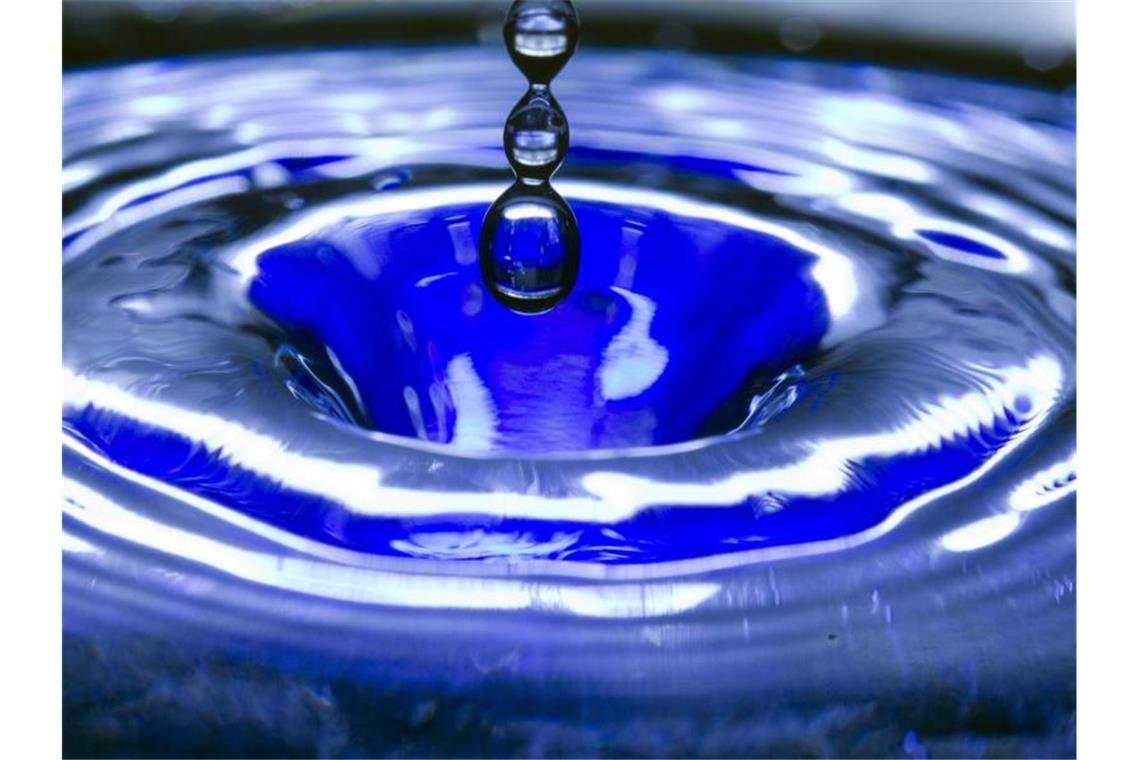 Ein Wassertropfen fällt in eine blaue Wasserschüssel. Foto: Jens Büttner/Archiv