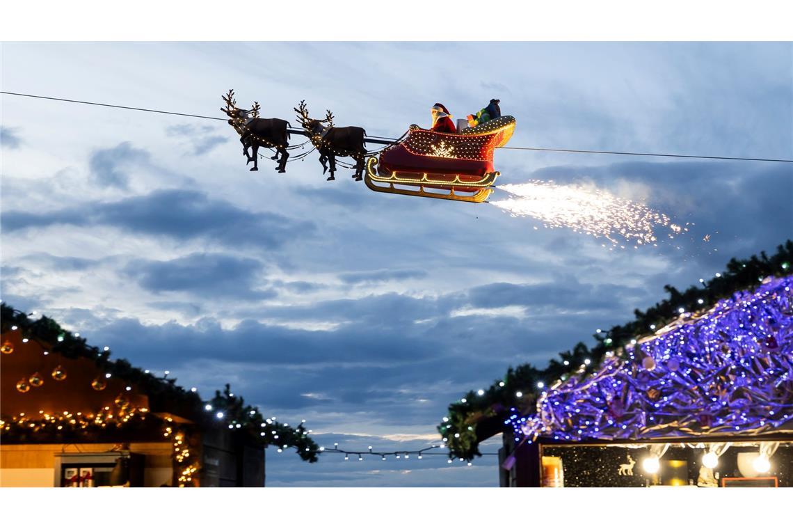 Ein Weihnachtsmann in einem fliegenden Schlitten ist in Montreux über den Weihnachtsständen vom Weihnachtsmarkt unterwegs.