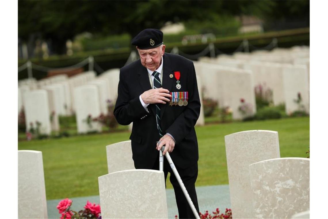 Macron richtet leidenschaftlichen Appell an Trump Ein Weltkriegsveteran bekreuzigt sich auf dem Soldatenfriedhof von Bayeux zum 75. Jahrestag des D-Day. Foto: Francisco Seco/AP
