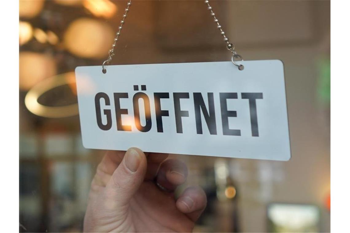 Ein Wendeschild mit der Aufschrift "geöffnet" wird umgedreht. Foto: Jörg Carstensen/dpa/Symbolbild