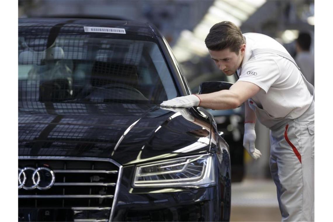Viruskrise kostet Volkswagen Milliarden Ein Werksmitarbeiter kontrolliert in einer Produktionshalle von Audi an einem Bandende einen A8. Foto: picture alliance / dpa/Symbolbild