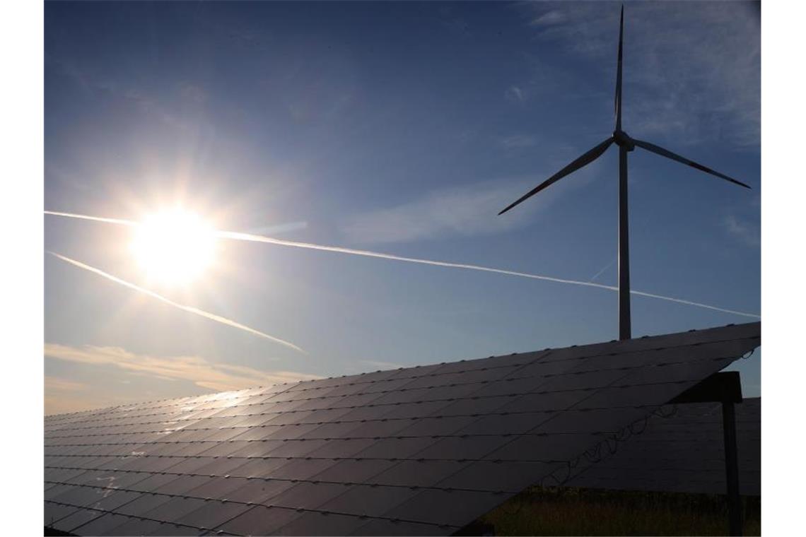 Ein Windrad steht hinter den Solarzellen einer Solarkraftanlage im Sonnenschein. Foto: Karl-Josef Hildenbrand/dpa