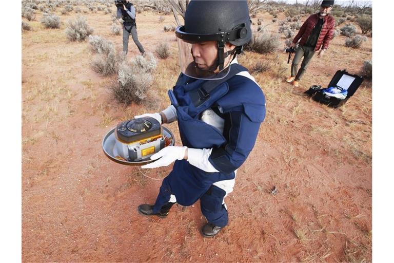 Ein Wissenschaftler hält in der Wüste des Woomera-Testgeländes für Luft- und Raumfahrt im Süden Australiens die Probenkapsel der japanischen Raumsonde „Hayabusa2“. Foto: -/JAXA/AP/dpa