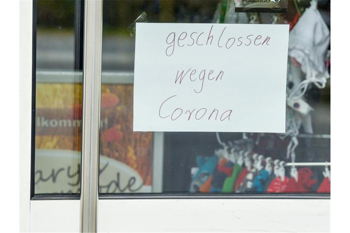 Ein Zettel mit der Aufschrift „geschlossen wegen Corona“ klebt an der Tür eines Geschäfts. Foto: Patrick Pleul/dpa-Zentralbild/dpa