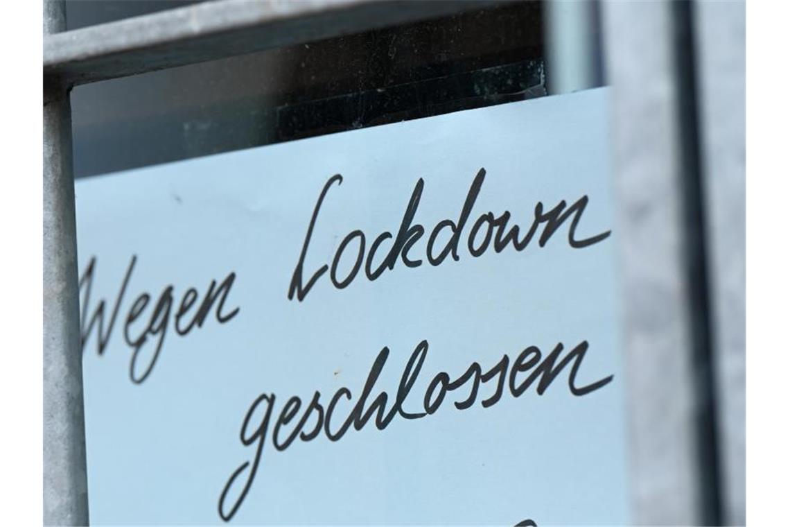 Ein Zettel mit der Aufschrift „Wegen Corona geschlossen“ hängt am Schaufenster eines Geschäfts. Foto: Arne Dedert/dpa