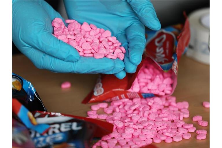 Ein Zollbeamter hält Ecstasy Tabletten in der Hand, die am Flughafen Köln/Bonn sichergestellt wurden. Foto: Oliver Berg/dpa