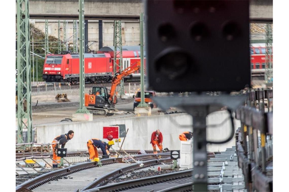 Fernzüge fahren drei Wochen lang an Ulm vorbei Ein Zug fährt im Hauptbahnhof an Gleisbauarbeitern vorbei. Foto: Stefan Puchner/dpa