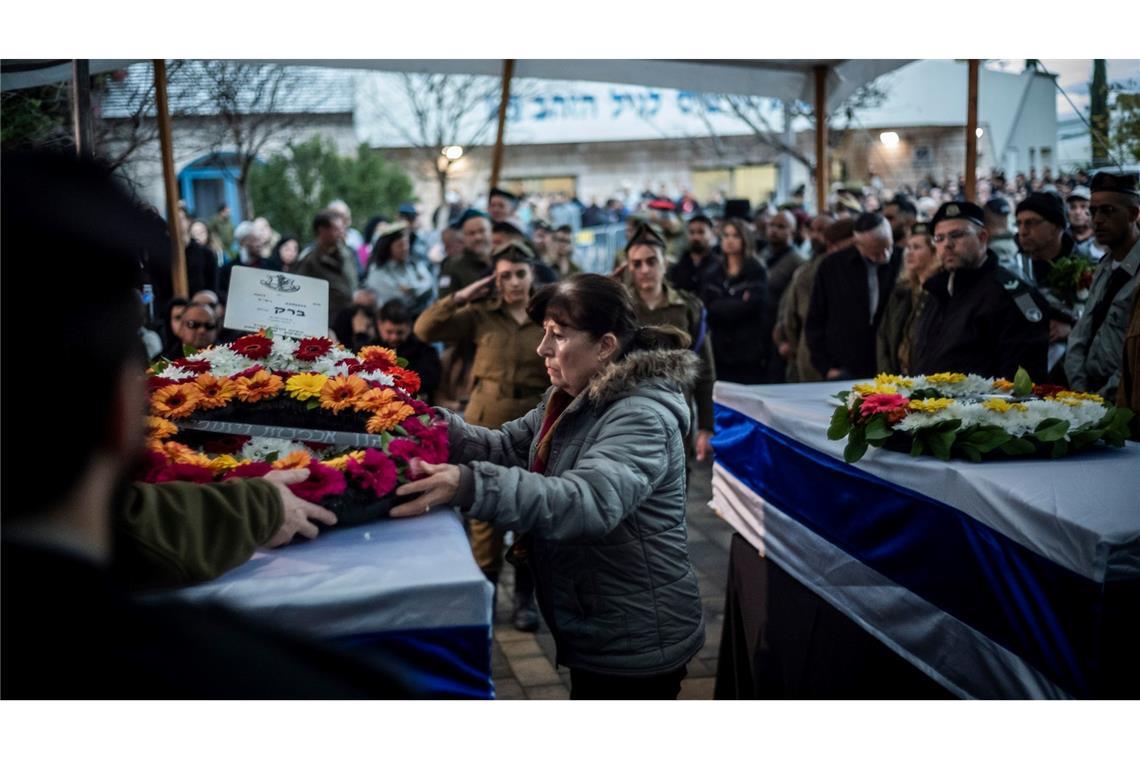 Eine 76-jährige und dessen 48-jähriger Sohn kamen nahe der Grenze zum Libanon durch Raketen der Hisbollah ums Leben. Viele Menschen nahmen heute im israelischen Mevo'ot HaHermon an der Beerdigung teil und trauerten. Wie diese Frau, die einen Blumenkranz auf einem Sarg ablegt.