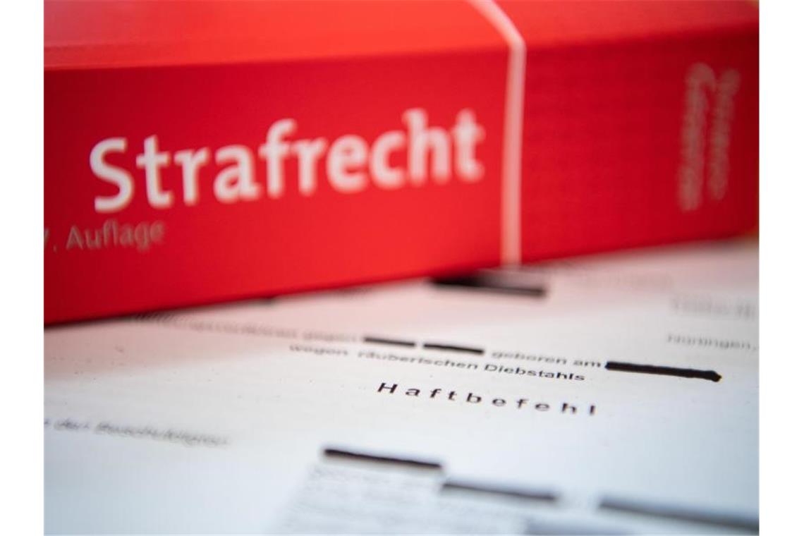 Eine Abschrift eines Haftbefehls liegt mit einem Strafrecht-Buch auf dem Tisch. Foto: Tom Weller/dpa/Illustration