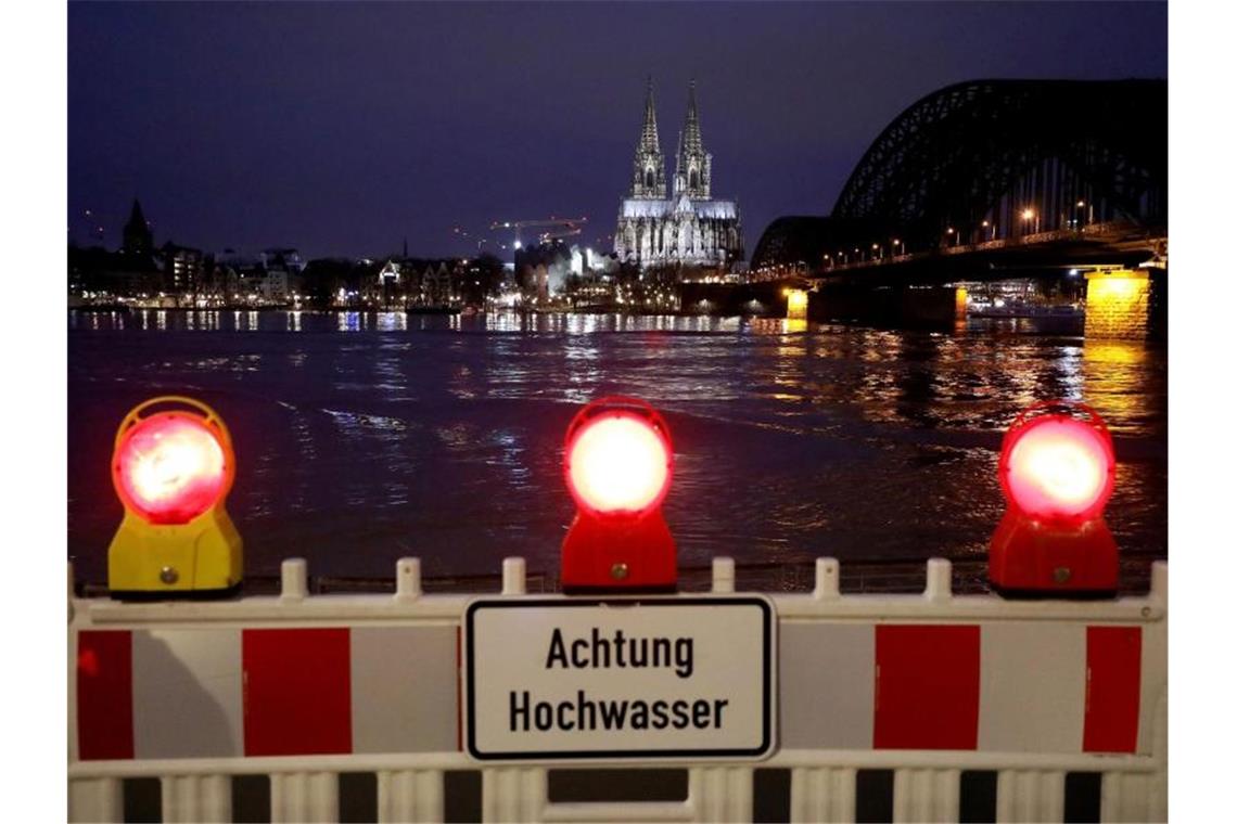 Eine Absperrung steht am Rheinufer. In Köln steigt der Pegelstand, für die Schifffahrt gibt es erste Einschränkungen. Foto: Oliver Berg/dpa