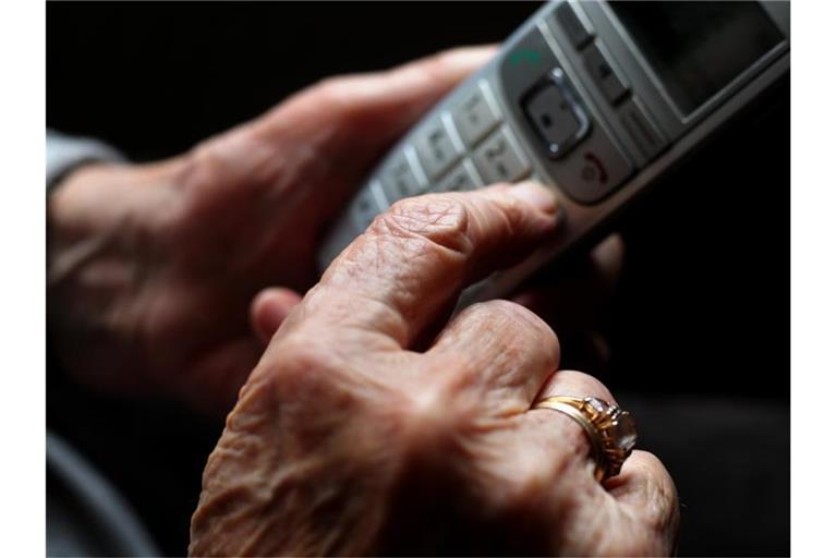 Eine ältere Frau tippt auf einem schnurlosen Festnetztelefon. Foto: Karl-Josef Hildenbrand/dpa/Symbolbild