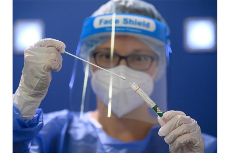 Eine Ärztin der Kassenärztlichen Vereinigung Sachsen hält in der Corona-Teststation für Urlaubsrückkehrer am Flughafen Dresden International einen Coronavirus-Test in den Händen. Foto: Robert Michael/dpa-Zentralbild/dpa