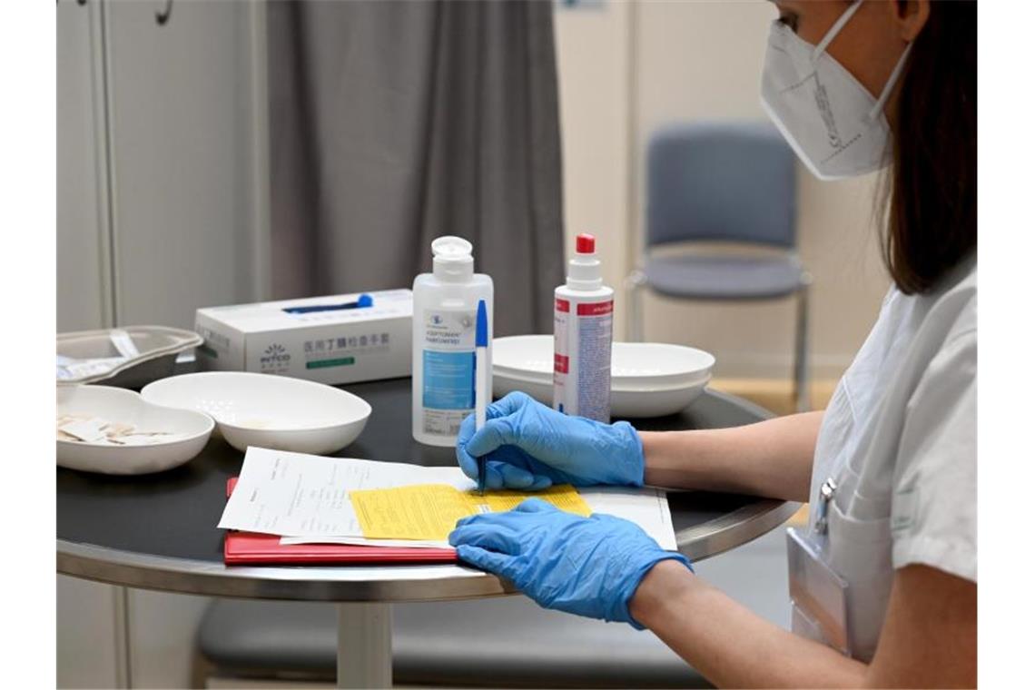 Mehr als 30 Millionen Menschen haben erste Impfung erhalten Eine Ärztin füllt nach einer Corona-Impfung im Impfzentrum des Klinikums Stuttgart einen Impfpass aus. Foto: Bernd Weißbrod/dpa