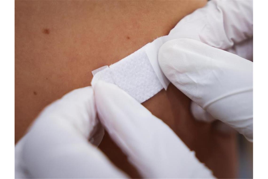 Eine Ärztin klebt einem Mann nach der Impfung ein Pflaster auf den Arm. Foto: Christian Charisius/dpa/Symbolbild