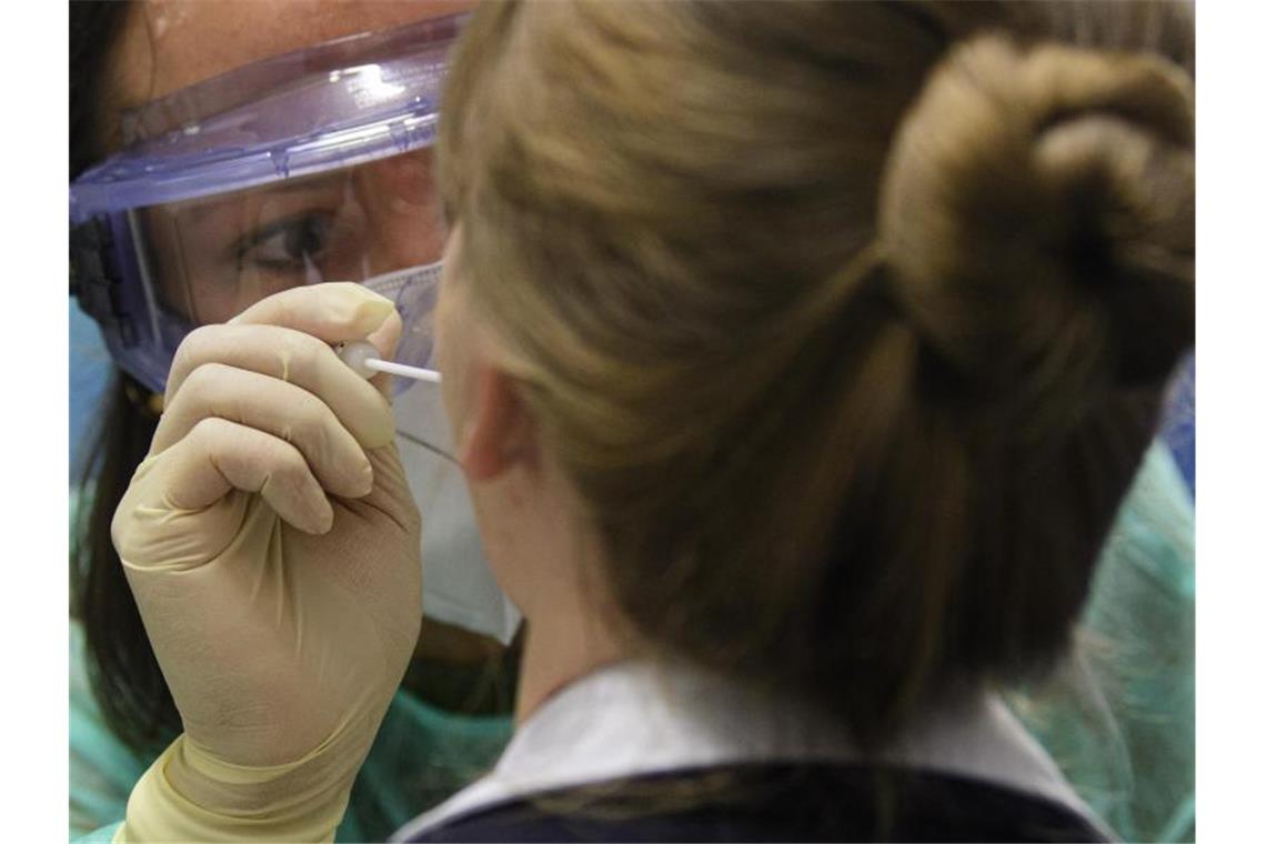 Eine Ärztin nimmt in der Corona-Teststation für Urlaubsrückkehrer am Flughafen Dresden International bei einer Frau einen Abstrich für eine Coronavirus-Test. Foto: Robert Michael/dpa-Zentralbild/dpa