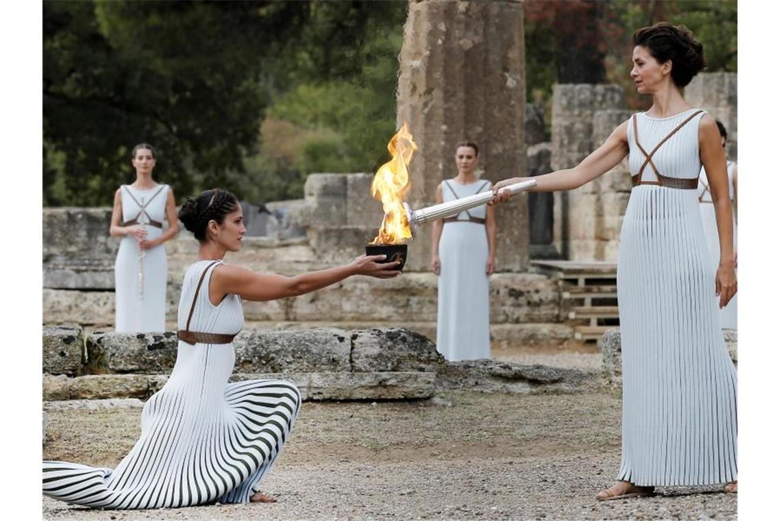 Eine als Hohepriesterin verkleidete Schauspielerin (2.v.r) entzündet 2017 in Olympia eine Fackel an einer Schale mit Feuer. Foto: Alkis Konstantinidis/POOL/dpa