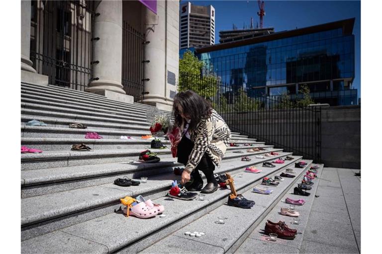 Eine Angehörige einer indigenen Volksgruppe legt eine Rose auf eines von 215 Paar Kinderschuhen auf den Stufen der Vancouver Art Gallery. Foto: Darryl Dyck/The Canadian Press via ZUMA/dpa