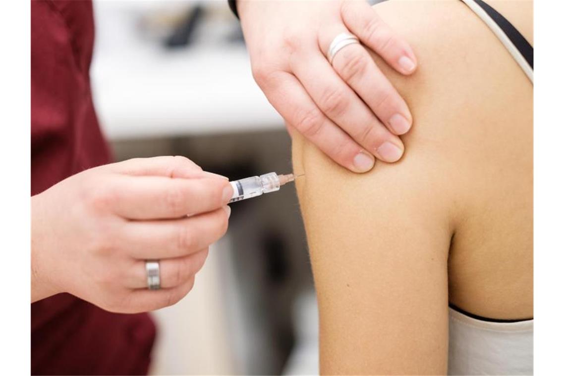 Eine Arzthelferin impft in einer Arztpraxis eine junge Patientin mit einer Spritze. Foto: Ole Spata