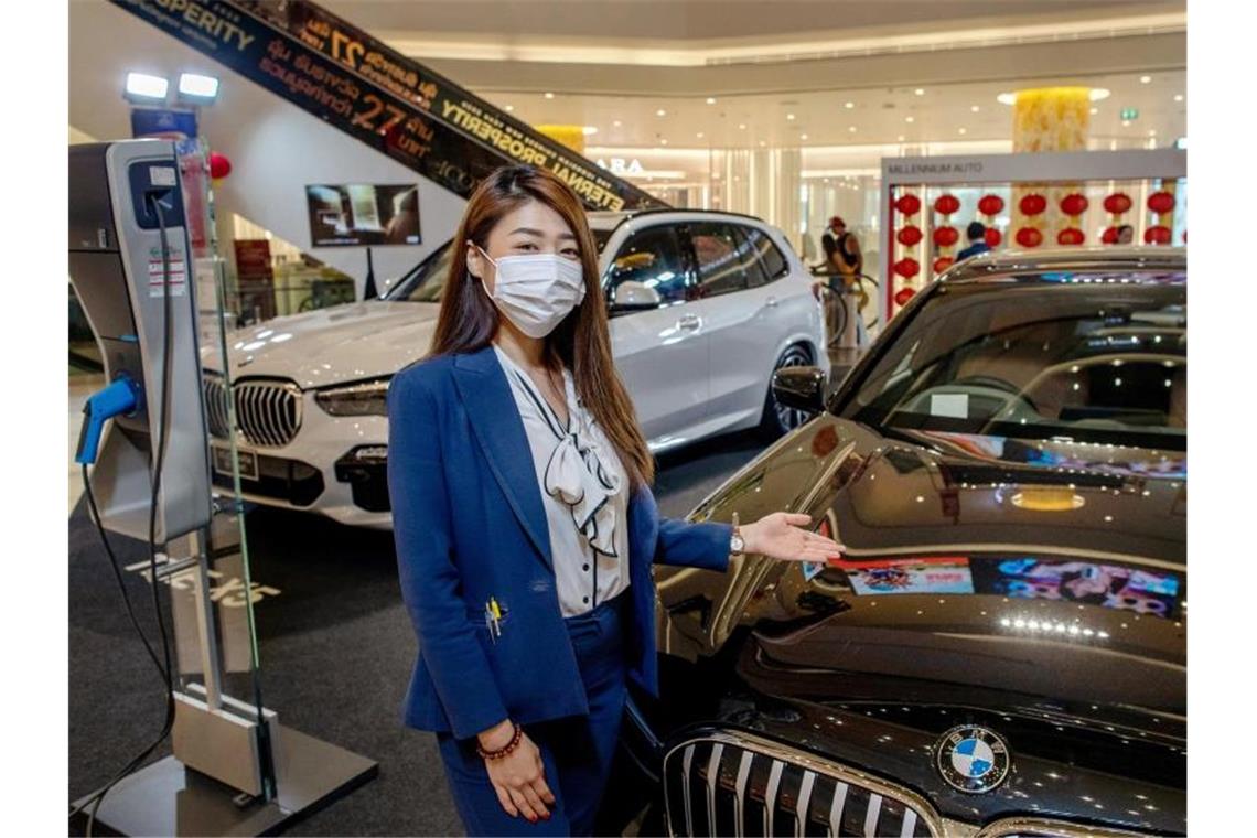 Eine Autoverkäuferin in Thailands Hauptstadt Bangkok trägt eine Schutzmaske. Foto: Gemunu Amarasinghe/AP/dpa