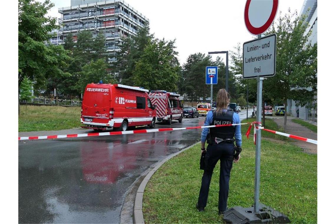 Eine Beamtin und Einsatzfahrzeuge der Feuerwehr auf dem Campus der TU Darmstadt. Foto: Alexander Rau/Keutz TV-News/dpa