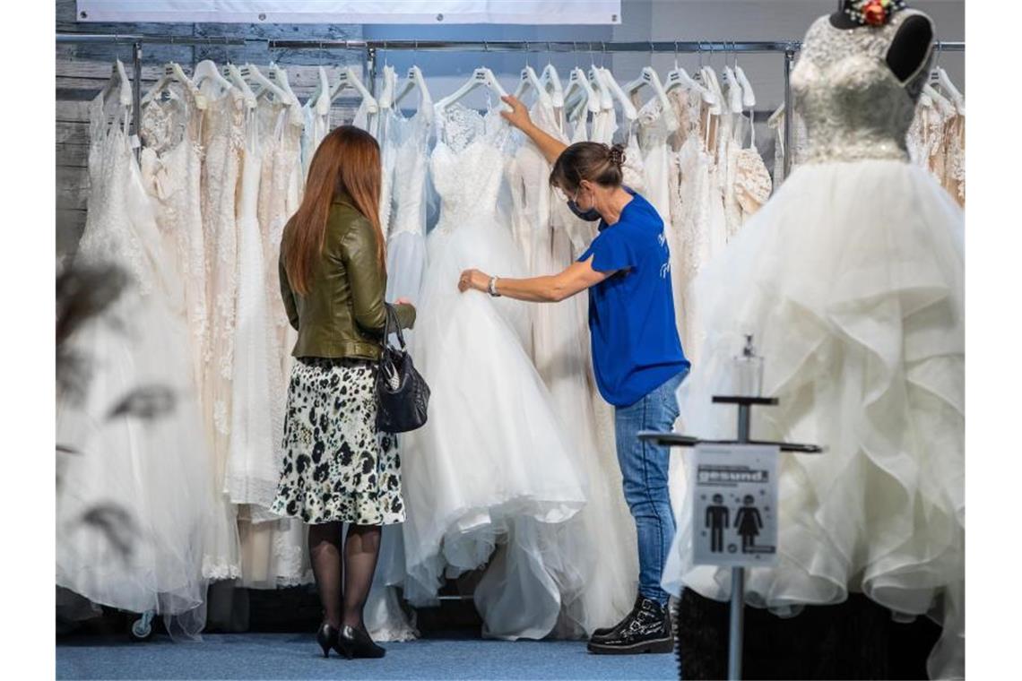 Fachleute erwarten erneut Verschiebung von Trauungen Eine Besucherin der Hochzeitsmesse sieht sich verschiedene Hochzeitskleider am Stand eines Ausstellers an. Foto: Christoph Schmidt/dpa