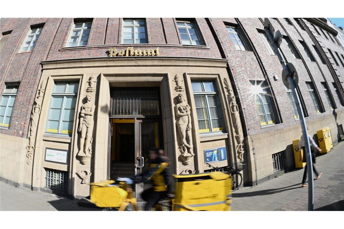 Post und Telekom haben noch Tausende Beamte Eine Briefträgerin fährt an einer Postfiliale vorbei - vielleicht ist auch sie eine Beamtin?