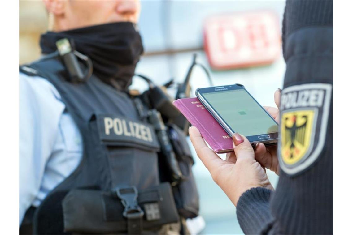 Eine Bundespolizistin scannt mit einem Mobiltelefon einen Reisepass. Foto: Klaus-Dietmar Gabbert