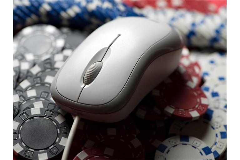 Eine Computermaus liegt auf einem Stapel Glücksspiel-Jetons. Foto: picture alliance / dpa