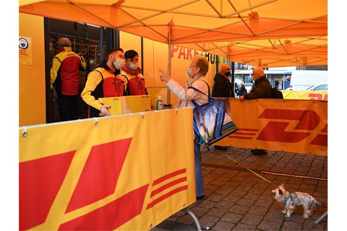 Eine Dame gibt bei Mitarbeitern eines DHL-Paketbusses in Berlin ein Paket ab. Foto: Britta Pedersen/dpa-Zentralbild/dpa