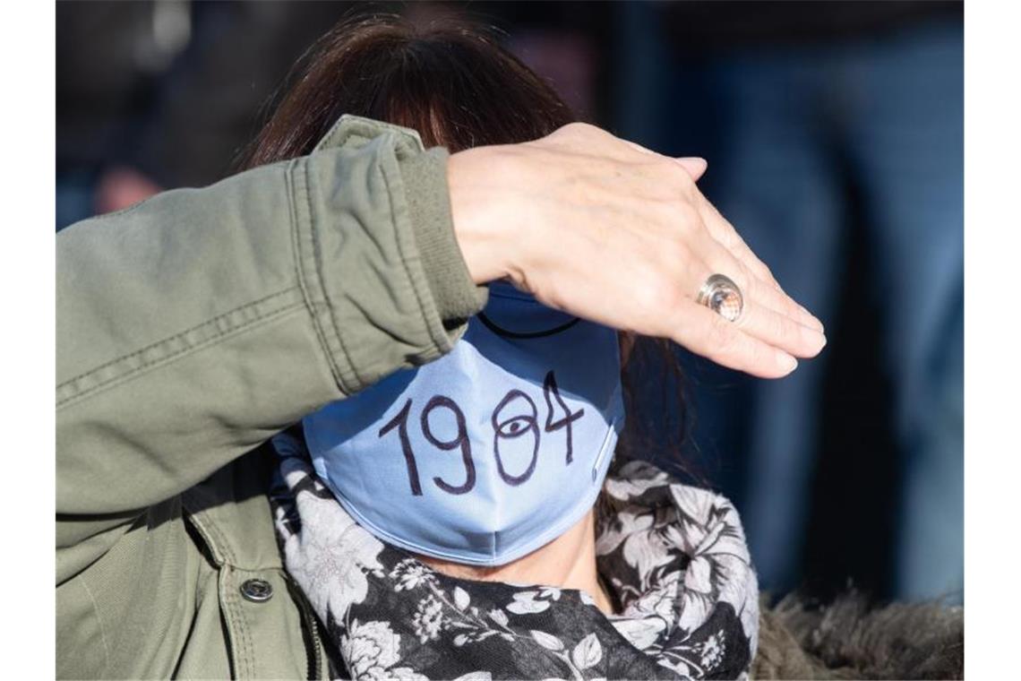 Eine Demo-Teilnehmerin trägt einen Mund-Nasen-Schutz mit der Aufschrift "1984" - in Anspielung auf den berühmten Roman von George Orwell. Foto: Sebastian Kahnert/dpa-Zentralbild/dpa