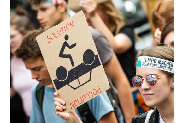 Eine Demonstrantin der Fridays-for-Future-Bewegung geht mit einem Plakat durch die Stadt. Foto: Christophe Gateau/Archivbild
