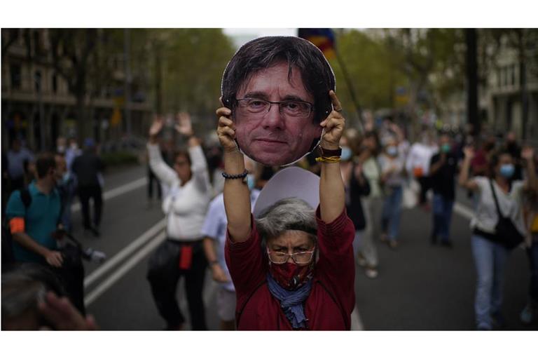 Eine Demonstrantin hält einen Pappausschnitt des ehemaligen katalanischen Regierungschefs Carles Puigdemont während einer Demonstration (Archivbild).