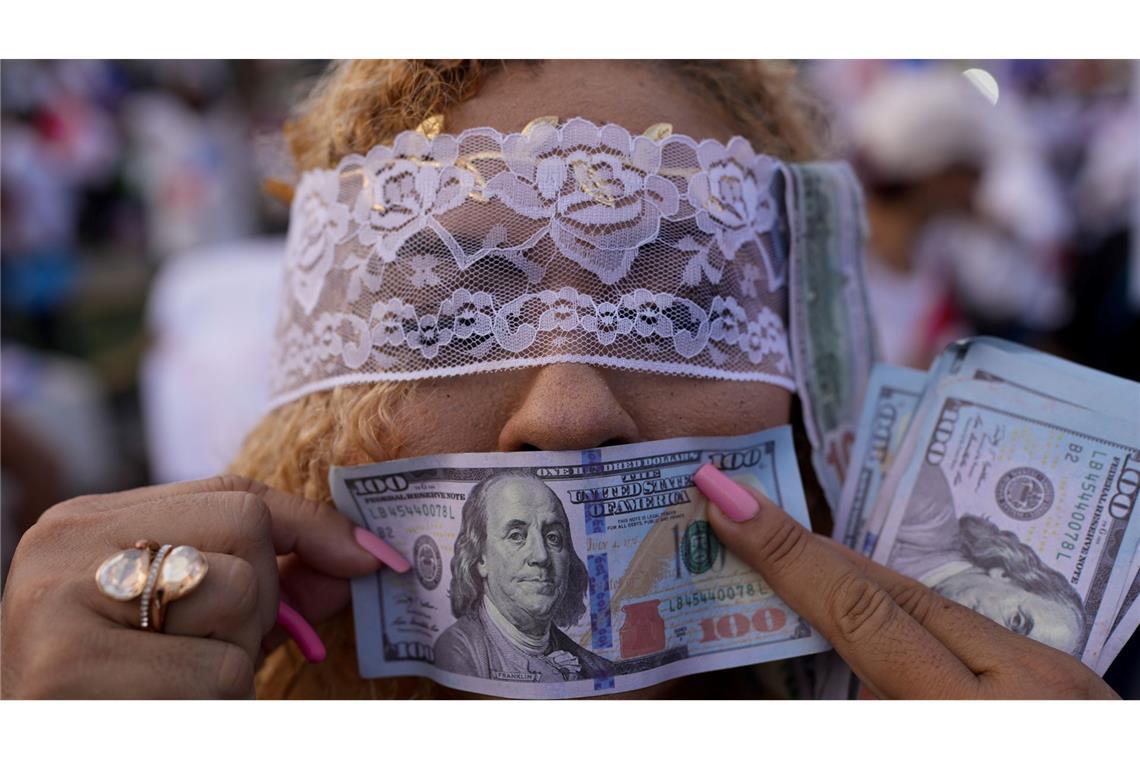 Eine Demonstrantin hält während einer Demonstration in Panama-Stadt gegen die Politik von Panamas Präsident Mulino eine falsche US-Banknote vor ihren Mund.