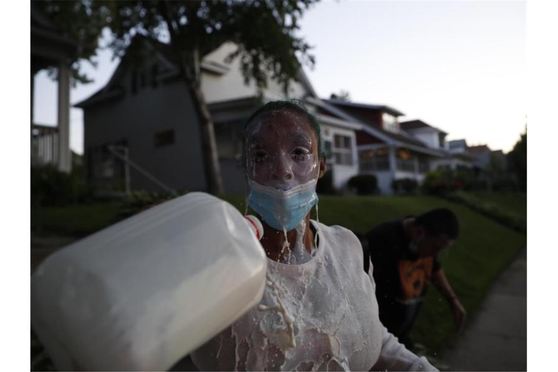 Eine Demonstrantin spült mit Milch ihre Augen aus, nachdem die Polizei Tränengas eingesetzt hatte. Foto: John Minchillo/AP/dpa