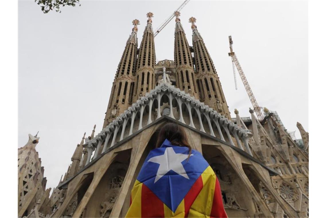 Eine Demonstrantin steht vor Barcelonas Wahrzeichen, der Sagrada Familia. Foto: Bernat Armangue/AP/dpa