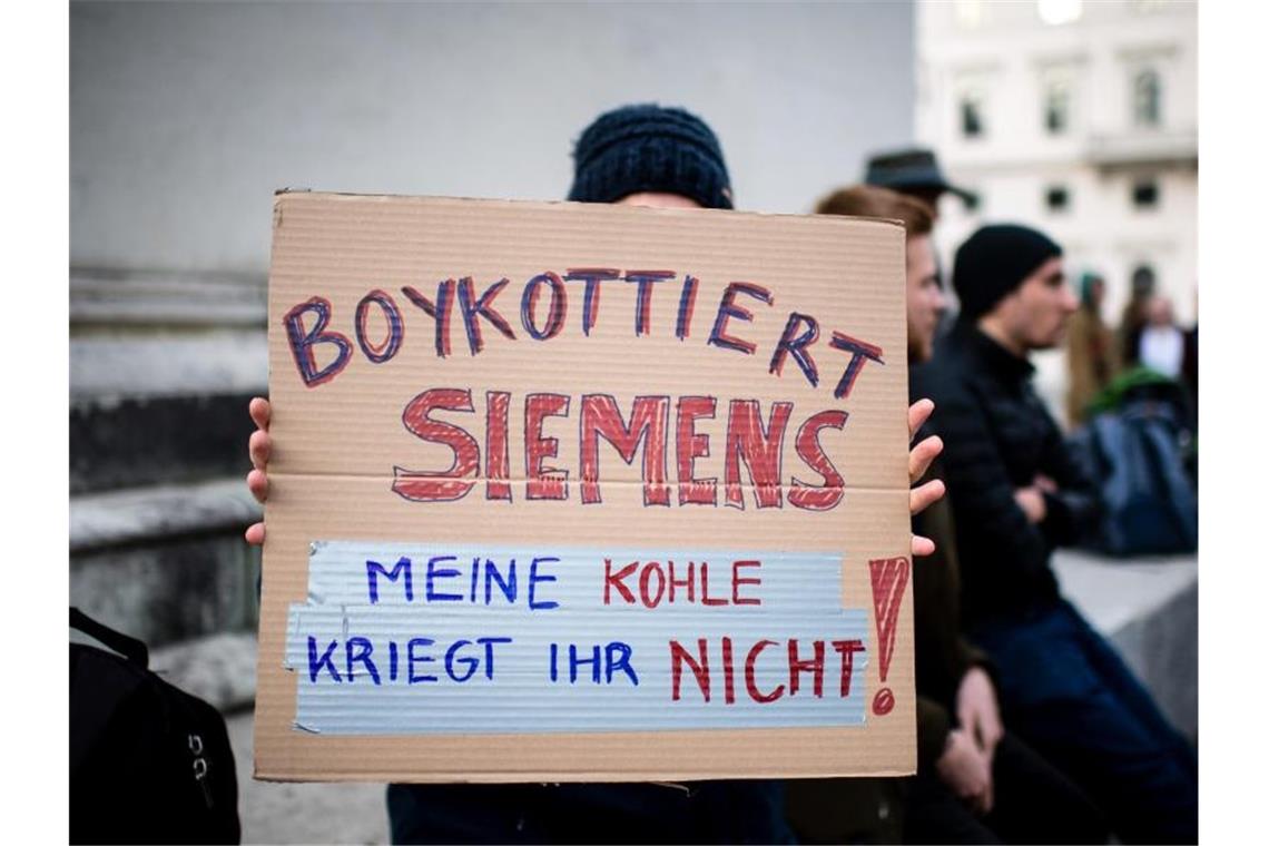 Eine Demonstrationsteilnehmerin hält während einer Protestaktion von Fridays for Future vor der Siemens Zentrale in München ein Schild in die Höhe. Foto: Matthias Balk/dpa