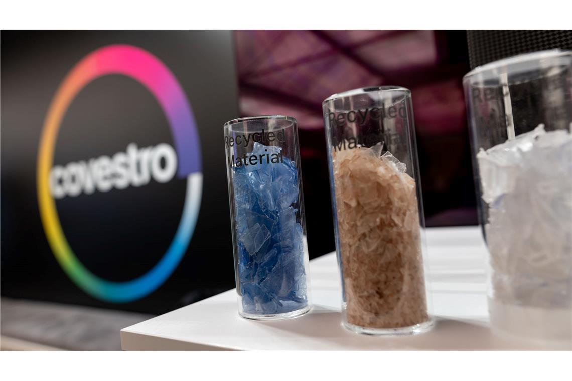 Eine deutsche Firma wird arabisch: Das Logo des Spezialchemie-Konzerns in einem Firmen-Showroom, davor Gläser mit Covestro-Materialien.