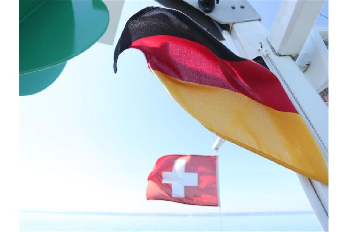 Eine deutsche und eine schweizerische Fahne hängen an einer Fähre. Foto: Karl-Josef Hildenbrand/dpa/Archivbild/Symbolbild