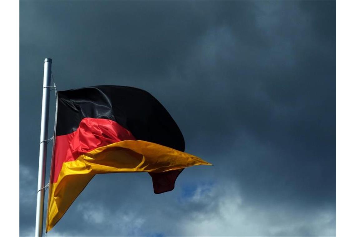 Eine Deutschlandfahne vor dunklen Wolken. Foto: Jens Kalaene/dpa-Zentralbild/dpa