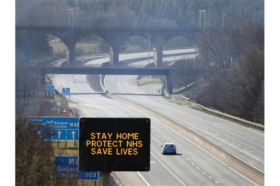 Eine digitale Anzeigentafel an einer Autobahn appelliert an die Fahrer, möglichst zu Hause zu bleiben. Foto: Andrew Milligan/PA Wire/dpa