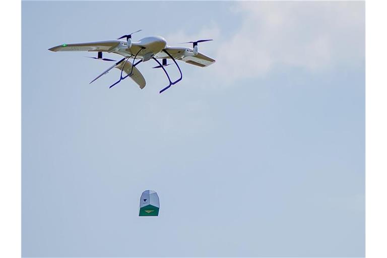 Eine Drohne des Start-Ups Wingcopter trägt ein Paket. Das mit Tragflächen ausgestattete Gerät kann senkrecht aufsteigen und dann auf der Strecke auch bei widrigen Wetterverhältnissen wie ein Propeller-Flugzeug fliegen. Foto: Wingcopter/dpa