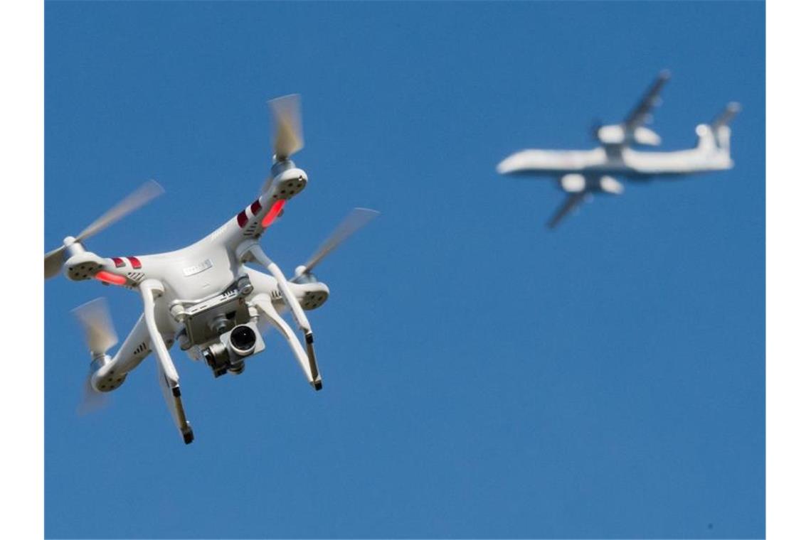 Eine Drohne ist in weiter Entfernung vor einem Flugzeug zu sehen. Foto: Julian Stratenschulte/dpa/Illustration