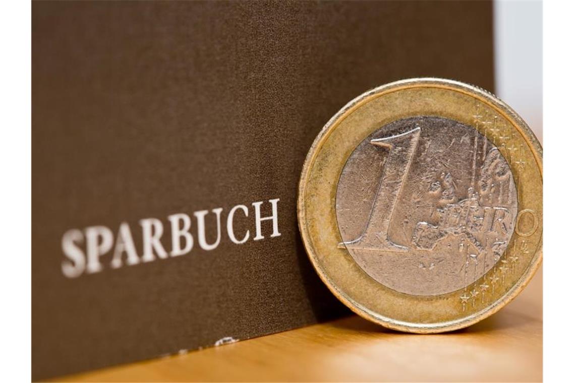 Baden-Württemberger erneut eifrigste Sparer Eine Ein-Euro-Münze steht am neben einem Sparbuch. Foto: Daniel Karmann/Archivbild