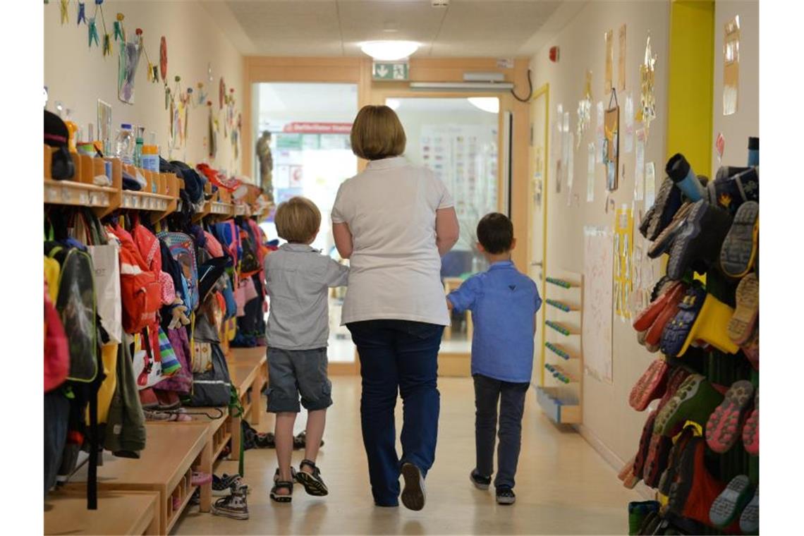 Eine Erzieherin geht mit zwei Kindern über den Flur. Foto: Jan-Philipp Strobel/Archivbild